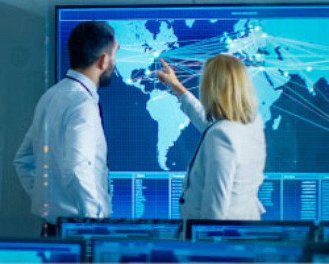 Man and woman studying a world map on a big computer screen