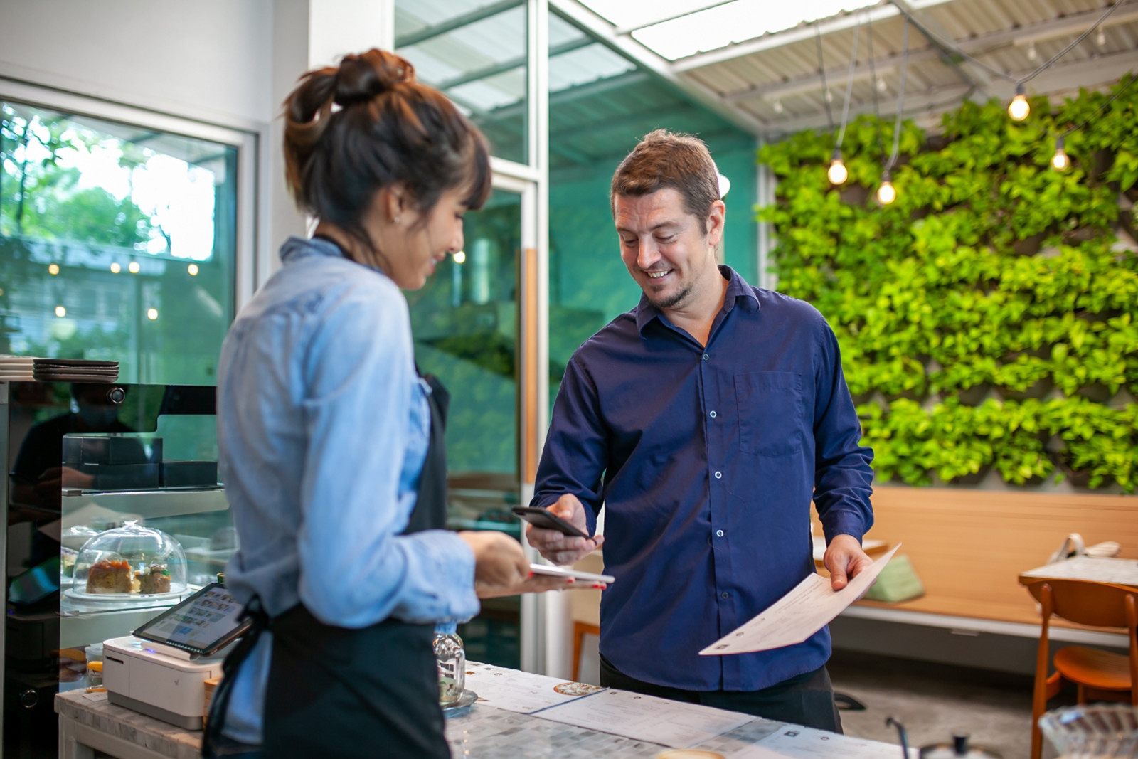 Man wearing apron smiling while serving food to customer