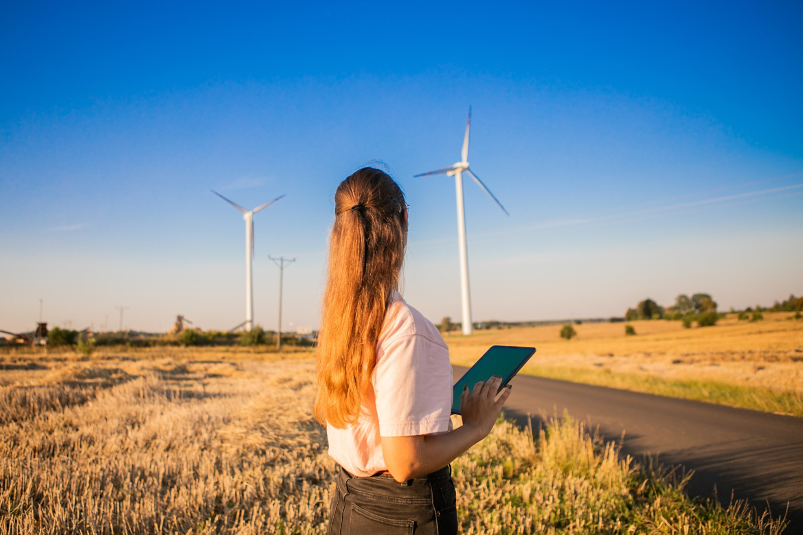 girl watching windmills and watching at tablets
