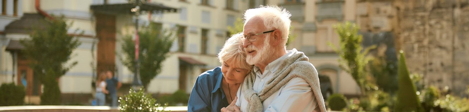 A senior couple walks hand in hand along a city sidewalk