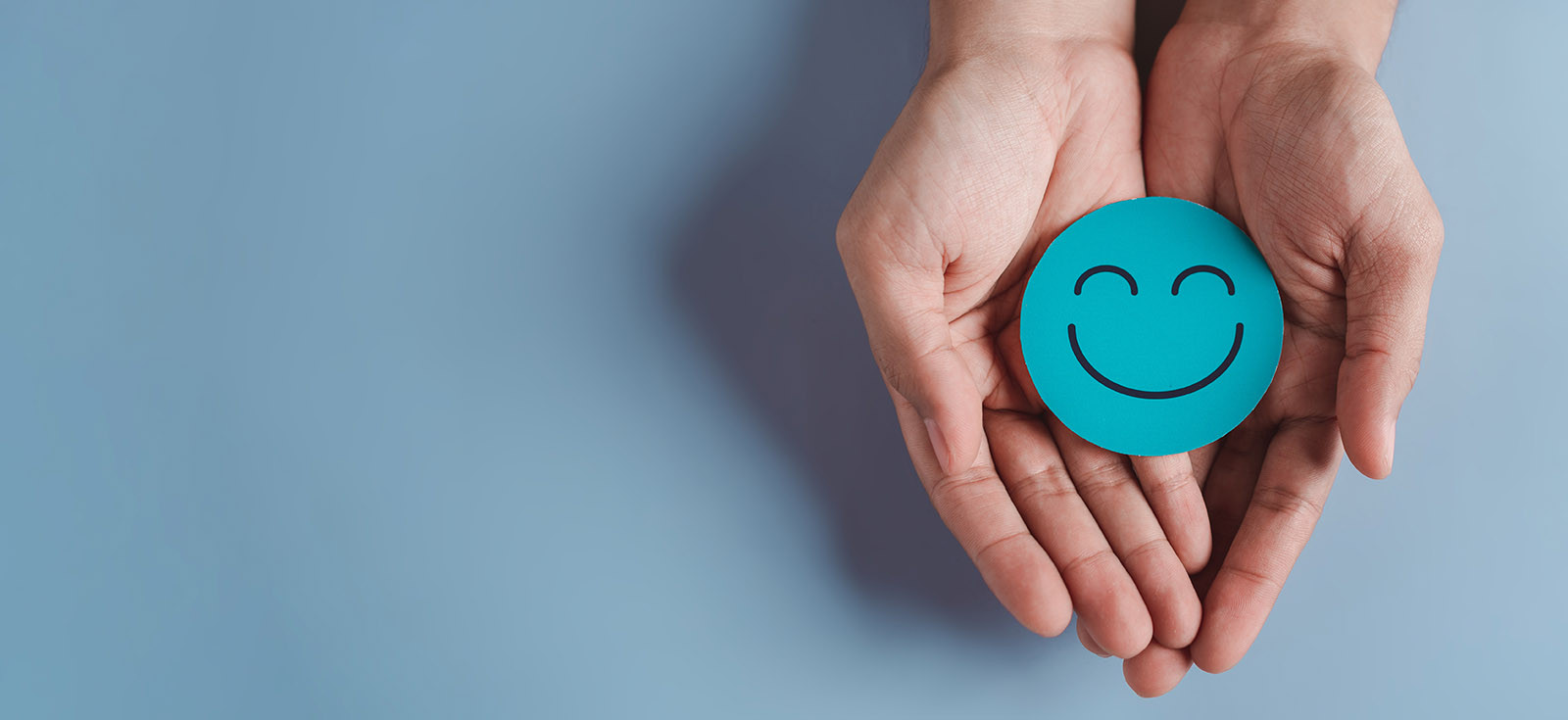 Hands holding blue happy smile face, good feedback rating, positive customer review, experience, satisfaction survey, smiley mental health, child wellness, world mental health day on blue background
