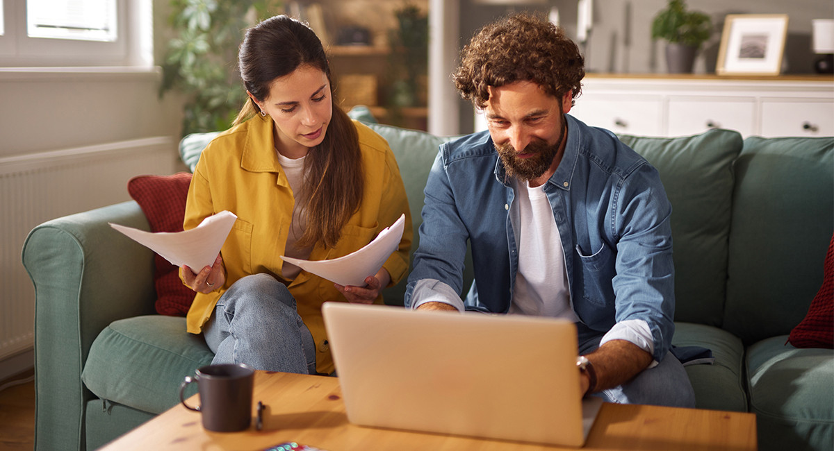 a man and women sitting on a sofa with a laptop