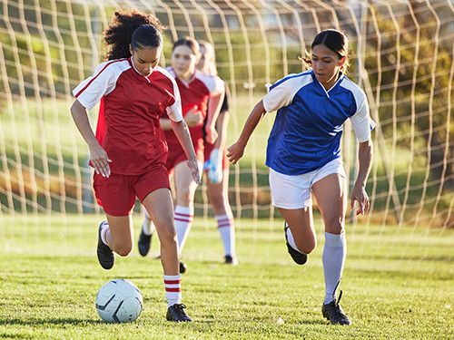 Girl in red kit playing football