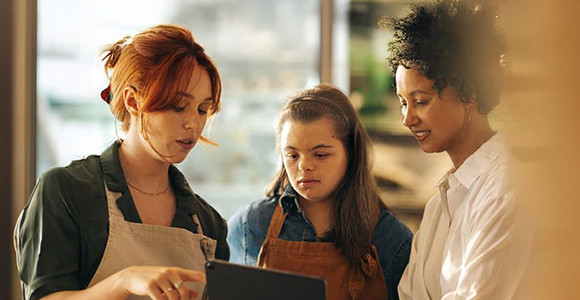 Store staff reviewing information on tablet together in workplace setting