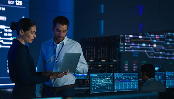 A group of diverse individuals seated around a table, each using a laptop for collaborative work.