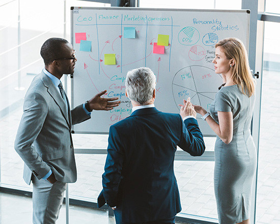 A man and woman stand beside a whiteboard, engaged in discussion