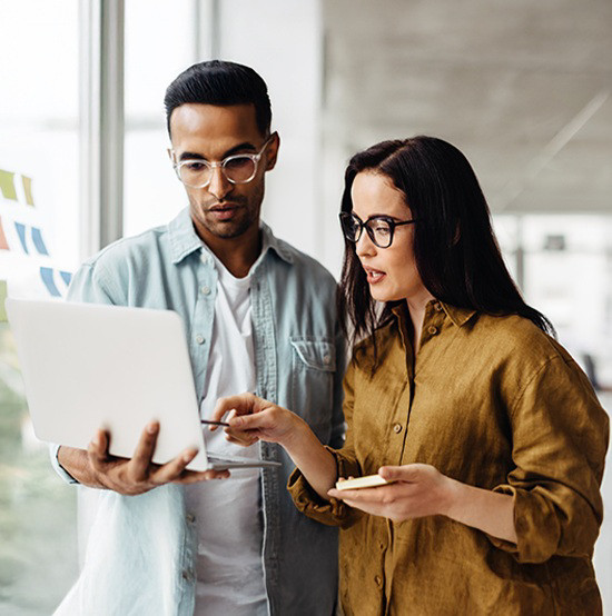 a man and women standing and looking at the laptop