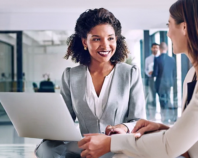 Two women discussing each other with laptop in office environment
