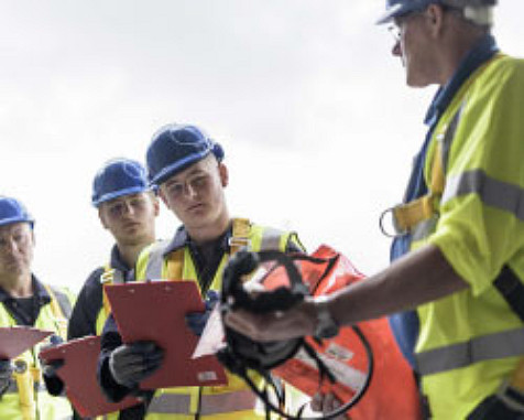 Quatre hommes portant gilets de sécurité et casques sur un chantier