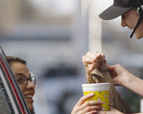 Photo d'une jeune femme recevant un sac en papier et une boisson chaude des mains d'un équipier de restaurant rapide