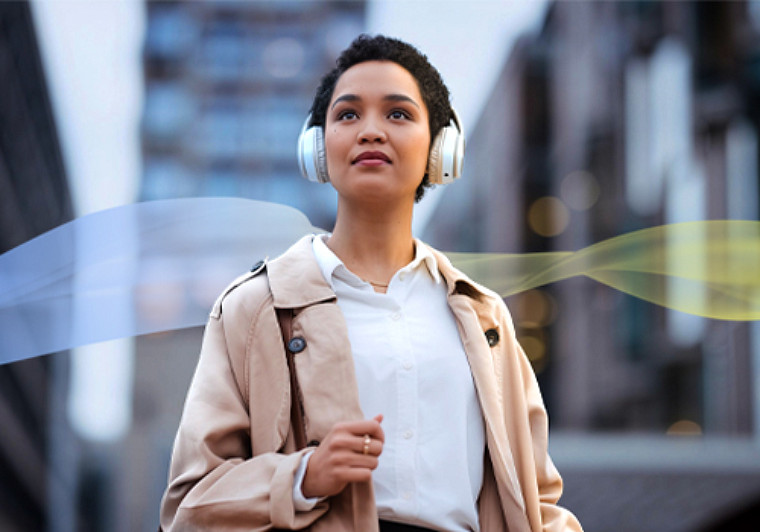 A woman with headphones stands amidst a vibrant cityscape