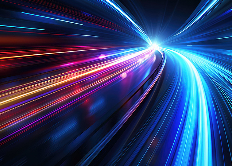 Abstract light-speed motion trails in blue, red, and orange converging toward a bright central point, evoking rapid forward movement and acceleration.