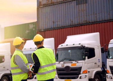 trabajadores de pie delante de camiones