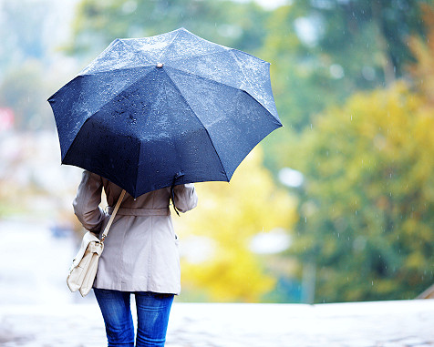 Frau steht draußen mit Regenschirm
