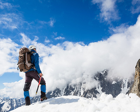 homme escaladant une montagne enneigée