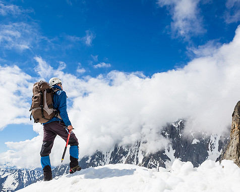 Mann klettert auf einen verschneiten Berg