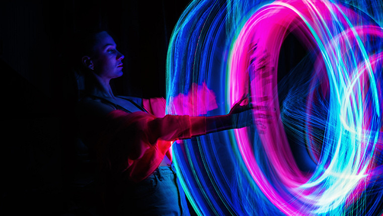 fotografía de una mujer con los brazos extendidos y remolinos de luz