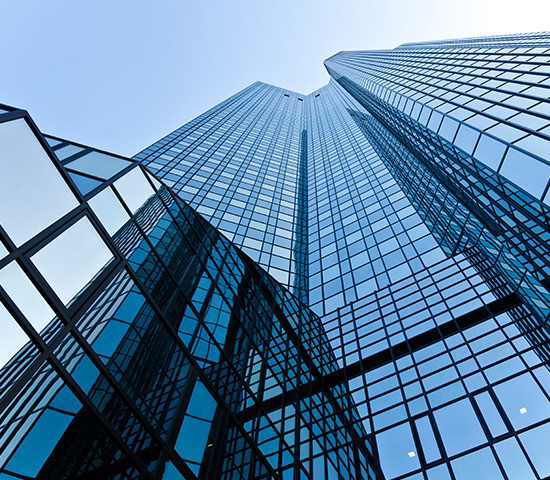 Un imposant immeuble de banque avec des façades vitrées dans lesquelles se reflète le ciel.