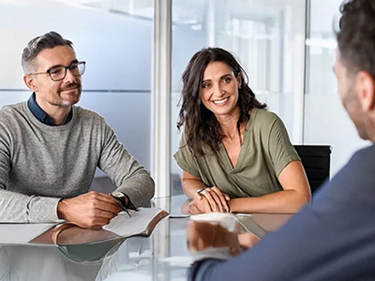 Three people in a meeting at workplace sitting across a table