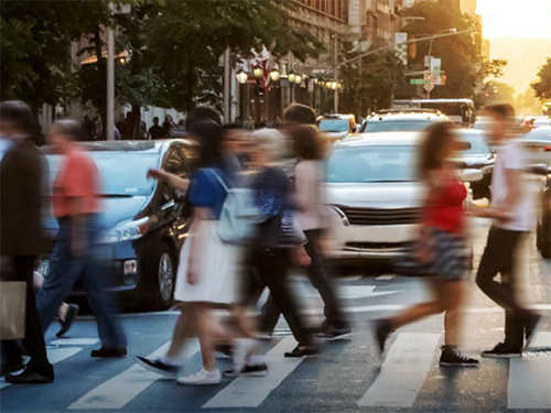 Pedestrians crossing a busy urban intersection during rush hour.