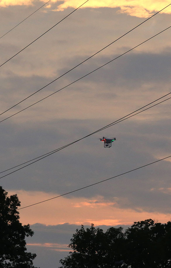 drone flying by powerloines at sunset