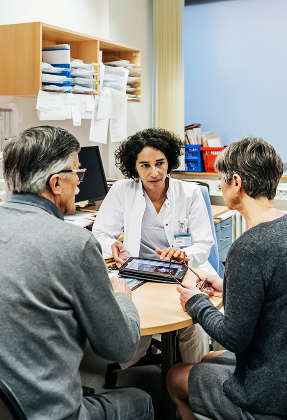 Doctor and patients in discussion pointing to tablet device