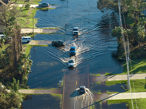 Vista aérea de los coches que evacuan y están rodeados de casas de agua en una zona residencial suburbana