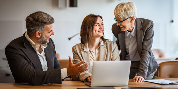 Professionals collaborating at a conference table with a laptop during a business strategy meeting.