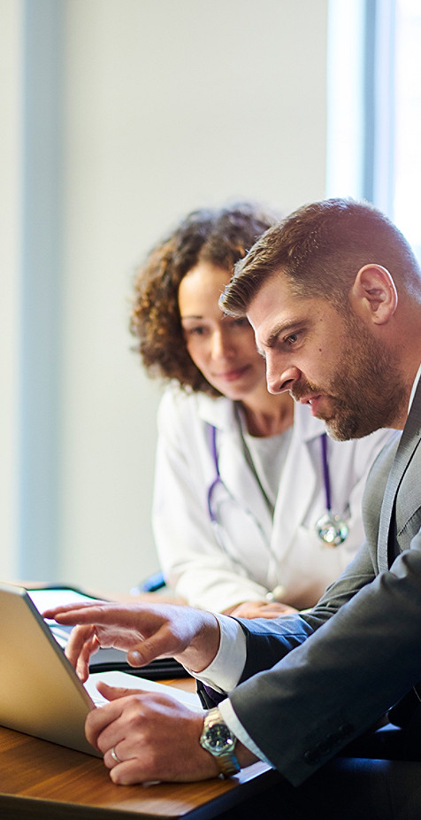 Deux professionnels de la santé regardant un écran d'ordinateur portable tout en essayant de résoudre un problème