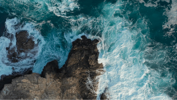 vagues bleues de l'océan frappant une falaise
