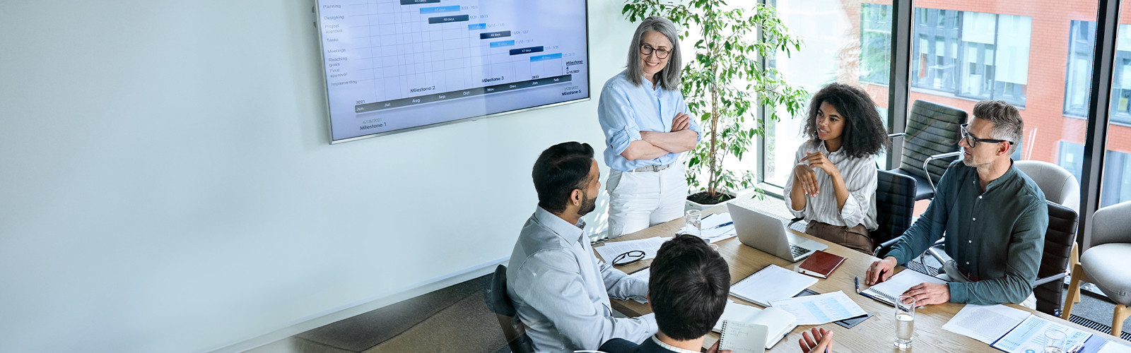 Team collaborating around table reviewing project timeline on wall screen