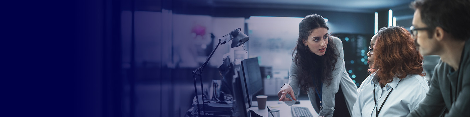 Professionals collaborating around computers in modern office environment with digital