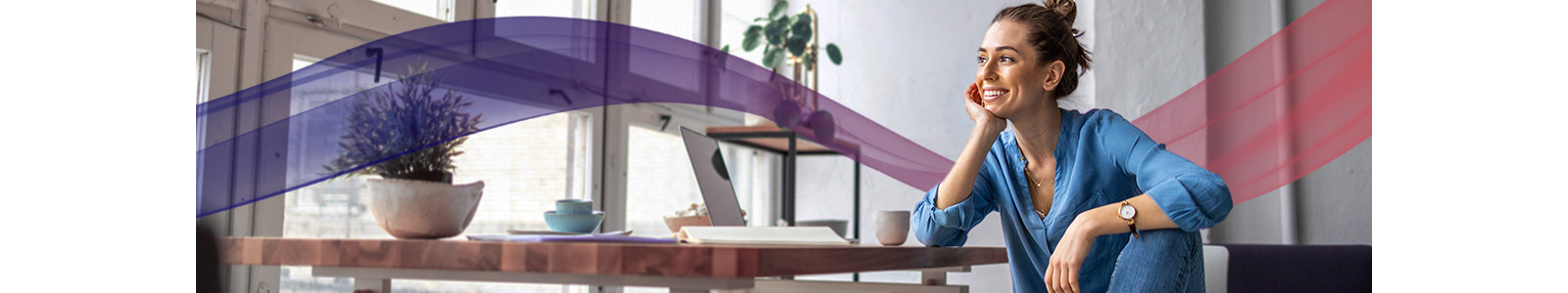 A woman is smiling while having a tea break in her workspace.