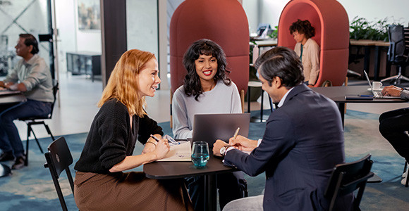 Two women and a man sitting around a table and talking