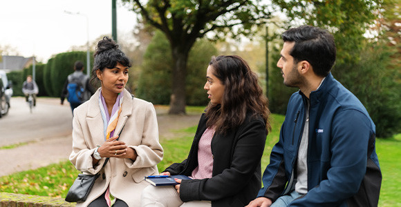 Two women and a man having a discussion outdoors