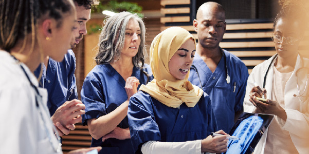 a nurse holding a x-ray discussing with a grup of doctors