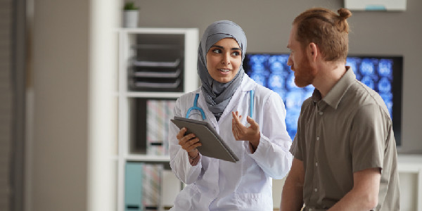 ein Arzt hält einen Notizblock in der Hand und diskutiert mit einem Patienten
