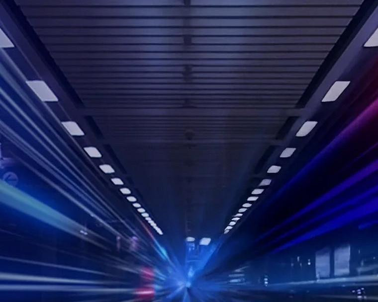 A long tunnel illuminated by light trails, with a train traveling through it, creating a dynamic sense of motion