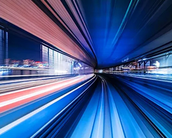 A blurry image of a train rapidly moving through a dark tunnel, emphasizing speed and motion