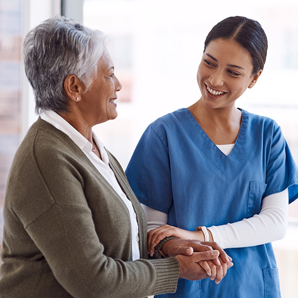 A nurse providing support to an elderly woman.