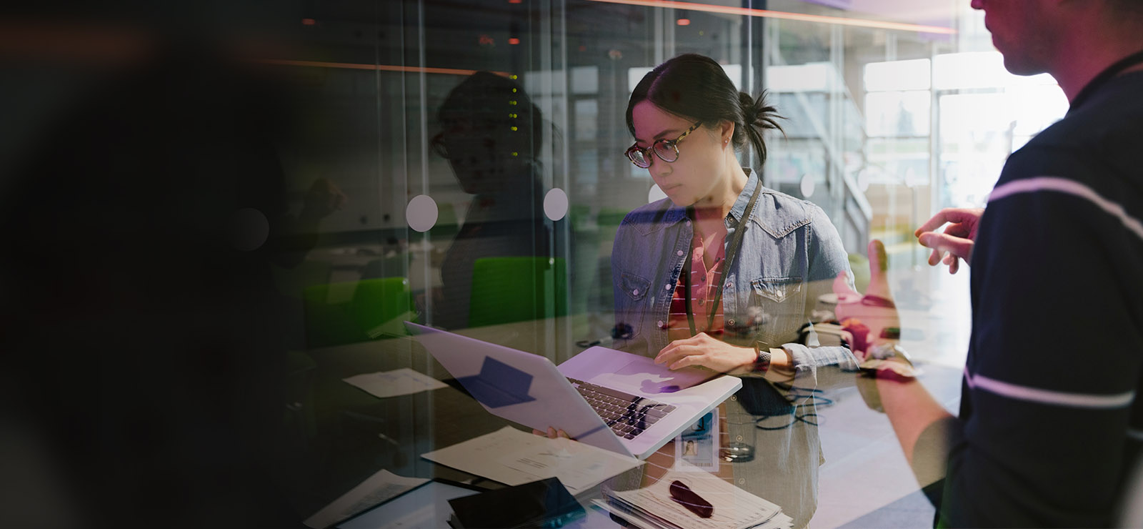 Woman working on a laptop while a man is standing next to her