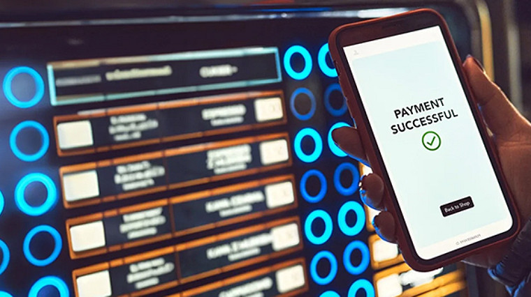 Mobile screen showing successful payment near a digital vending display