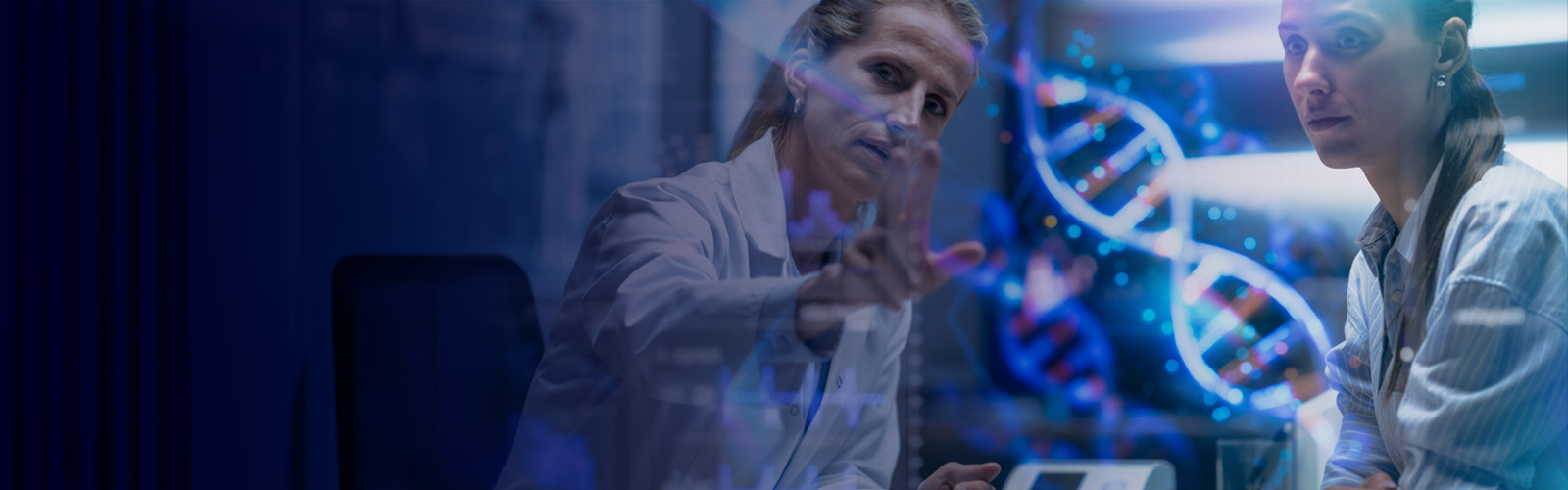 Two scientists in lab coats observe a computer display, likely reviewing experimental results or data analysis.