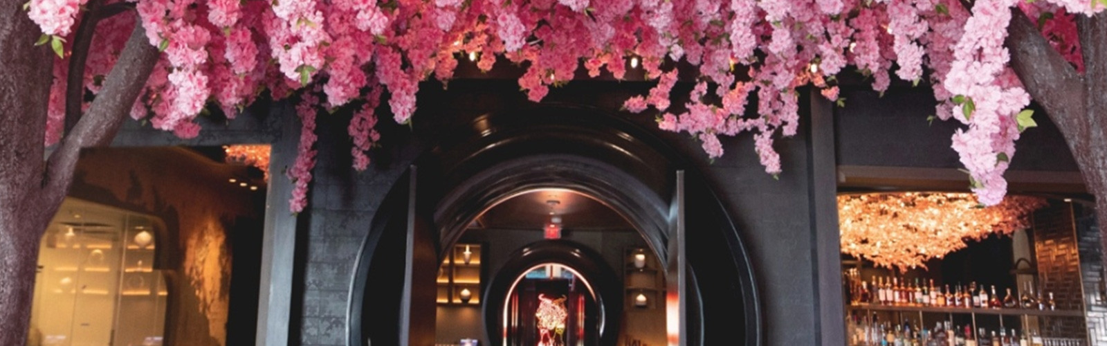 Entrance to a floral-themed bar with cherry blossom decor and a circular archway