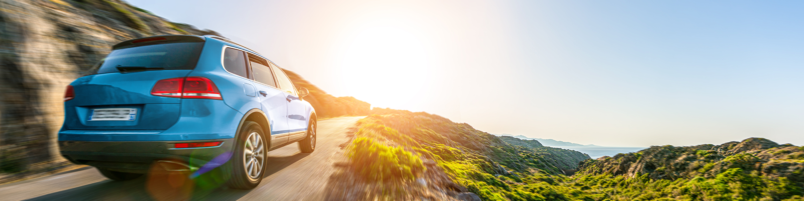 SUV navigating a winding mountain road surrounded by lush greenery and rocky terrain