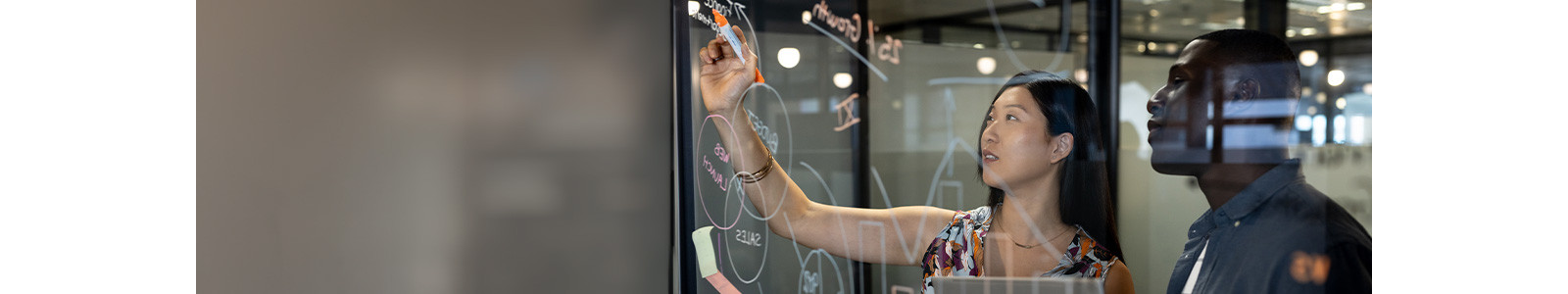 A person writing on a glass board