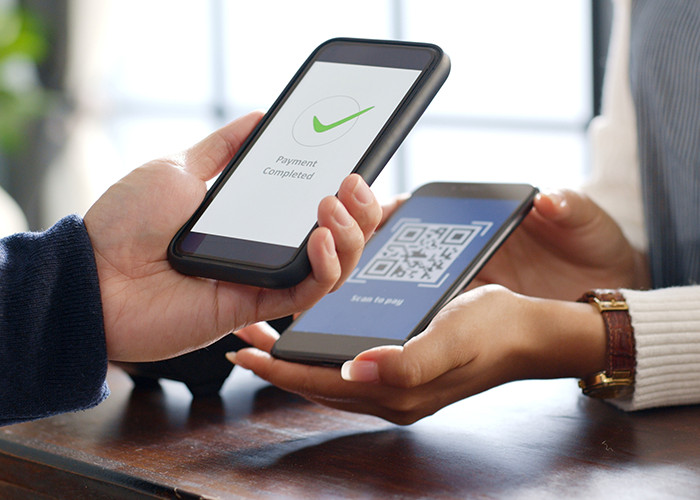 Two hands holding two phones next to each other making a transaction