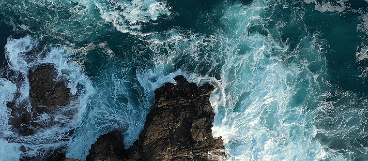 Aerial view of wavs crashing against a rock