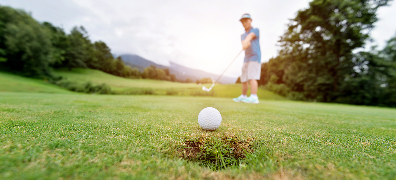 Boy putting golf ball on the hole