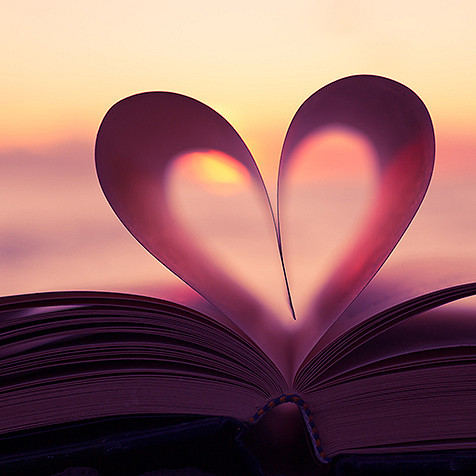 Et kjærlighetstegn dannet av to sider av en åpen bok på en mørk bakgrunn
